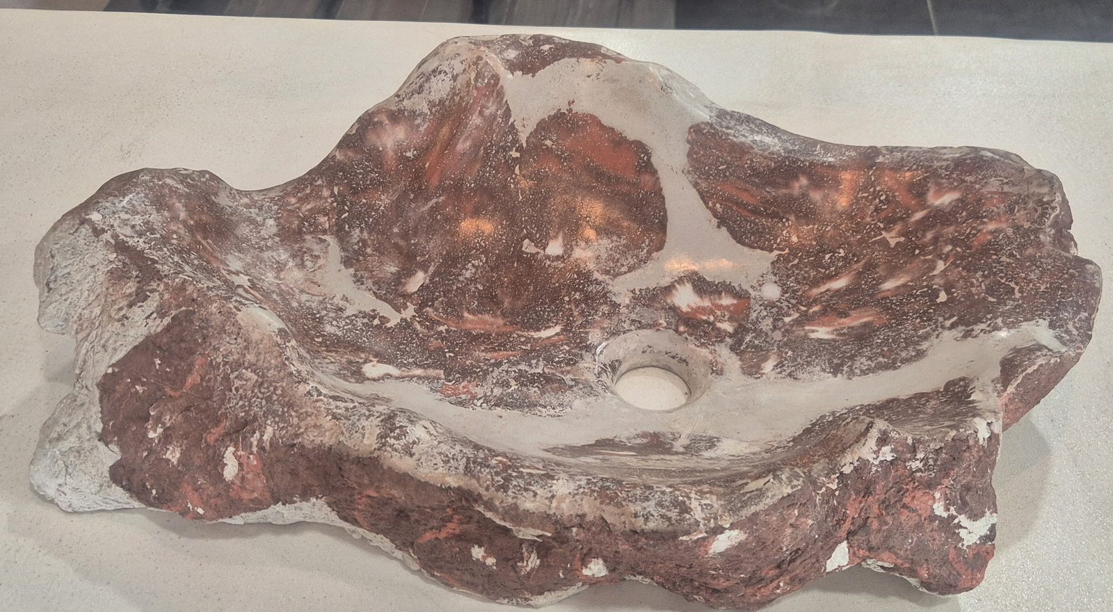 Detalle del desagüe del lavamanos La Roca en acabado rojo vino