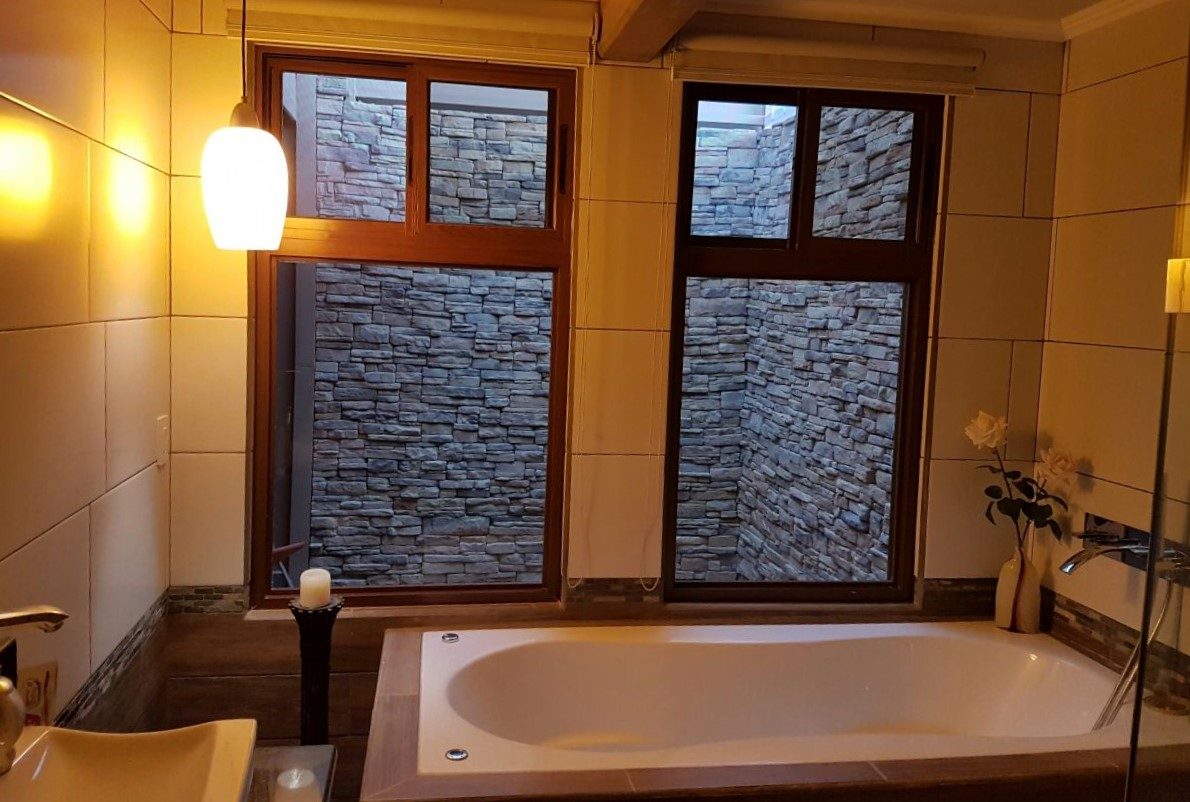 Baño con pared de piedra QuickFit Rustic alrededor de la tina